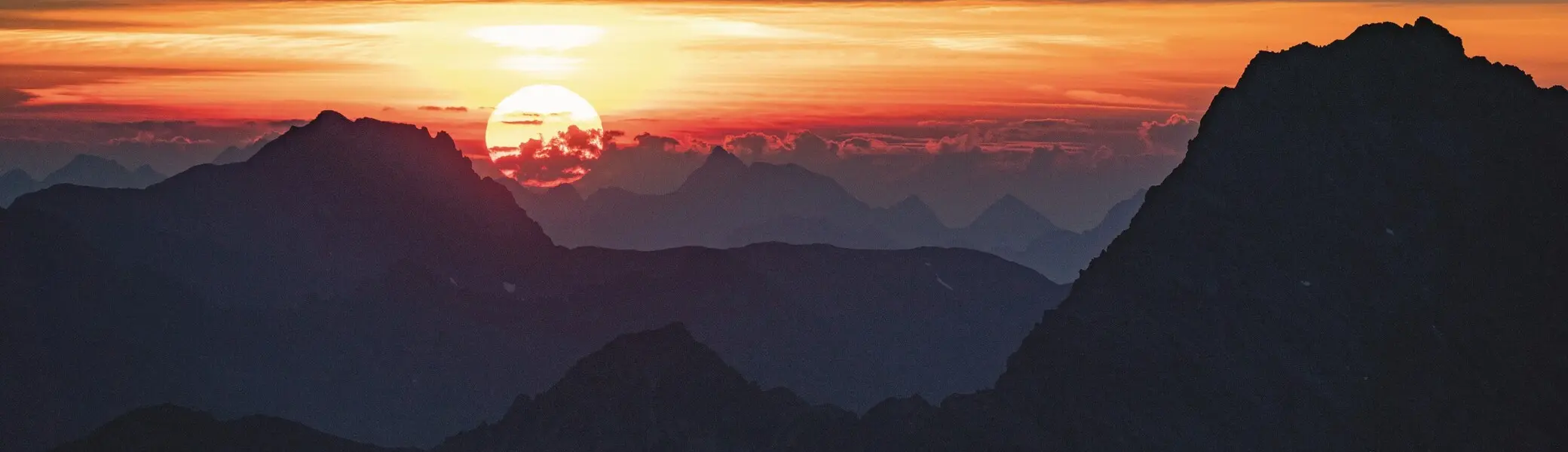 Sonnenuntergang über einer Berglandschaft im Ötztal mit silhouettenhaften Gipfeln und orange-rotem Himmel. | © Michael Heidenfelder