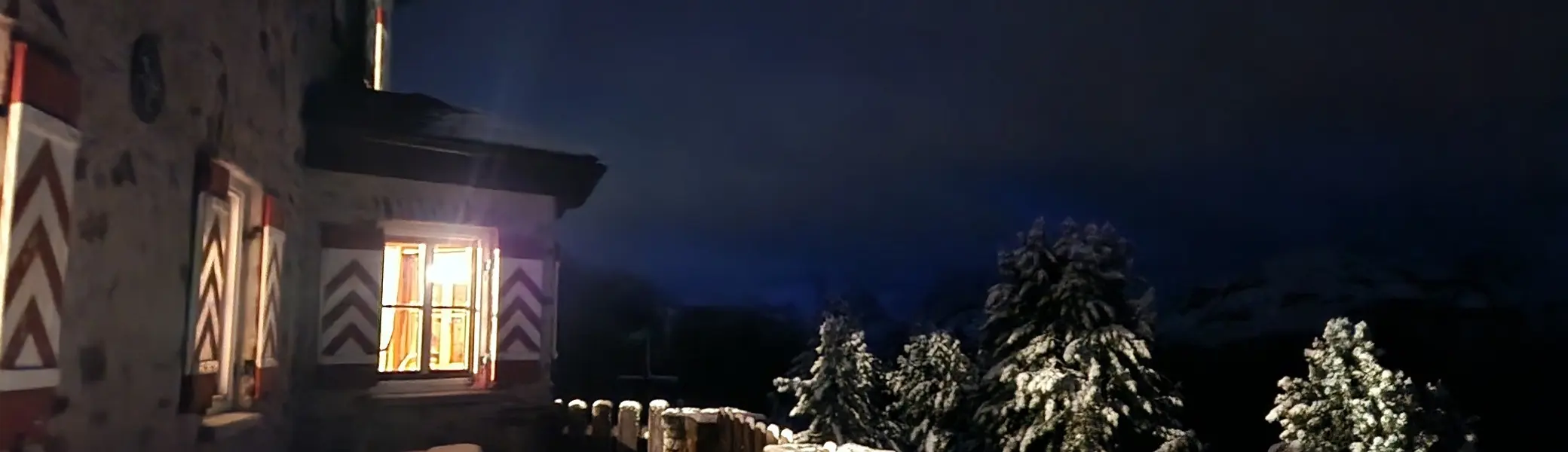 Winterabend in den Bergen: Während draußen Schnee und Dunkelheit die Landschaft prägen, strahlt aus den Fenstern der Hütte warmes Licht. Ein Ort der Ruhe und Geborgenheit inmitten einer beeindruckenden Bergwelt. | © Michael Heidenfelder